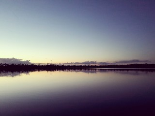 Forest and clouds reflecting on a lake in Estonia after sunset