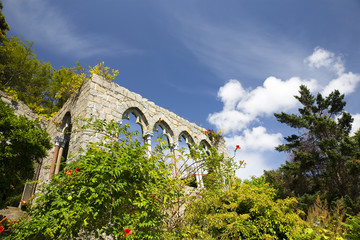 ruins of an ancient castle among flowers and trees. arched gallery on a background of blue sky. Copy space for your text