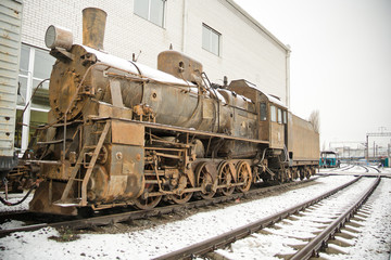 Old rusty steam locomotive on railroad in winter
