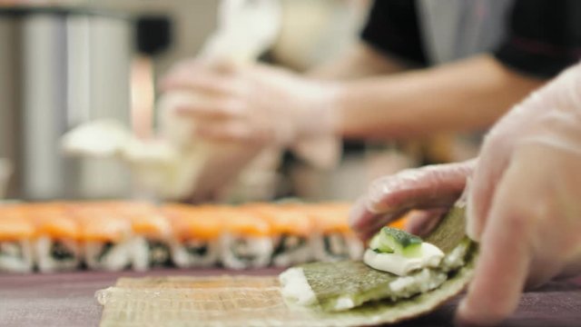 A chef is making Philadelphia rolls 