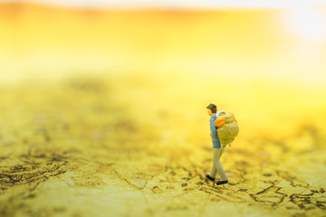 Travelling concepts. Traveler miniature mini figures with backpack walking on map