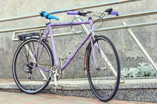 Old Road Bike Of Pink Color With A Ridiculous Seat Rewound Blue Electrical Tape. Cycling Or Commuting In City Urban Environment, Ecological Transportation Concept