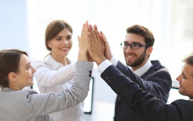 successful business team giving each other a high-five, standing in the office