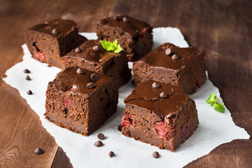 Dark chocolate brownies decorated with mint leaf on wooden table. Closeup view horizontal composition