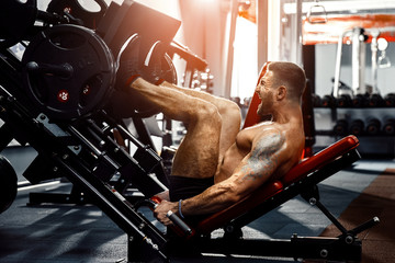 Man Using A Press Machine In A Fitness Club. Strong man doing an exercise on its feet in the...