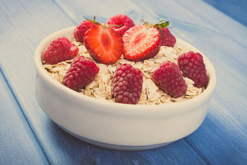 Vintage photo, Fresh oat flakes or oatmeal with strawberries and raspberries, healthy lifestyle and nutrition