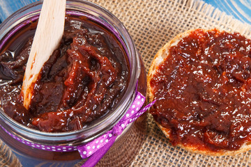 Wooden knife and plum marmalade or jam for preparing fresh sandwiches, healthy sweet breakfast concept