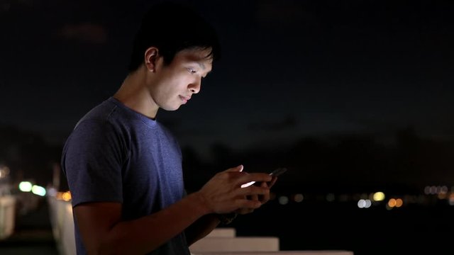 Man looking at mobile phone in city at night