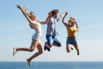 Carefree friends jumping by sea ocean.