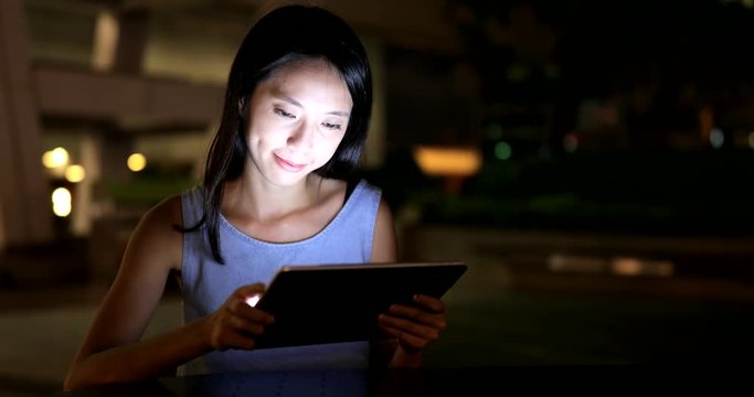 Woman looking at tablet computer in city at night
