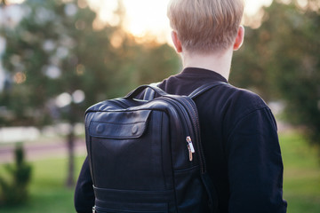 The guy with a black leather backpack. City landscape