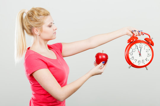 Happy woman holding clock, apple and measuring tape