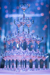 Pyramid of glasses champagne on wedding party. Champagne tower. Glass of tower in blue background.