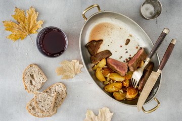 Slices of beef steak with potatoes in pan with wine