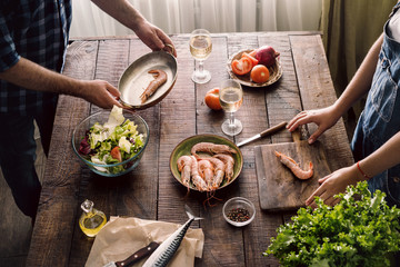 Couple cooking together shrimp dinner and salad of vegetables