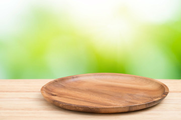 Empty wooden tray on perspective wooden table on top over blur natural background. Can be used mock up for montage products display or design layout.