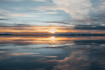 Symmetry view of Bonneville Salt Flats against cloudy sky at sunset