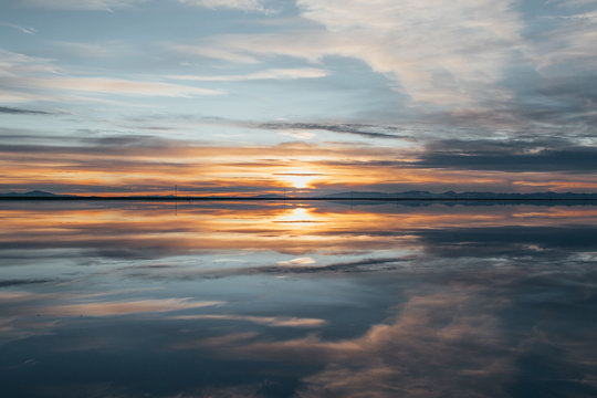 Symmetry view of Bonneville Salt Flats against cloudy sky at sunset