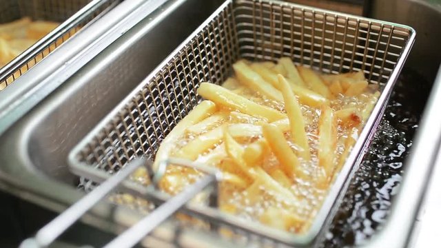 Male cook preparing delicious French fries at street cafe
