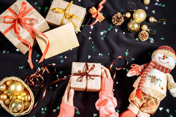 Female hands wrapping xmas gifts into paper and tying them up with red, brown and gold threads