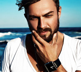 Portrait of handsome fashion man model wearing white clothes posing on blue sea background....
