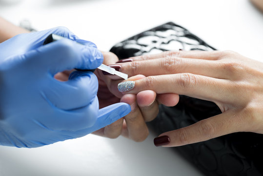 Manicure And Pedicure Series: Manicurist Applying Clear Nail Polish On Customer’s Gel Nail