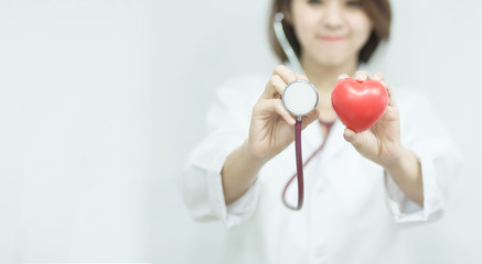 Close-up of female doctor holding red heart, in health checking concept.