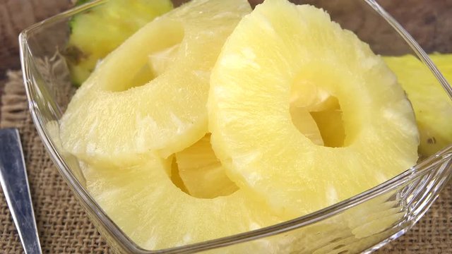 Portion of Preserved Pineapple pieces rotating on a wooden plate (not loopale; 4K)