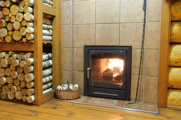 A wood burning stove. Wood stove and firewood in rural wooden house.