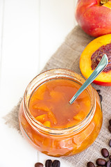 Nectarine (Peach, Apricot) coffee jam confiture in glass jar and spoon on white wooden background. Vertical. Selective focus. Copy space for your text.
