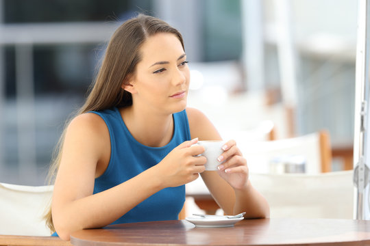 Pensive woman holding a coffee mug in a bar