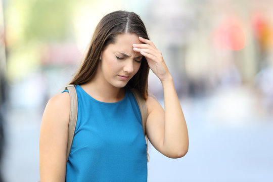 Woman suffering headache on the street