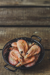 shrimp cooked on a black small frying pan (on a wooden surface)