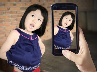 portrait of asian kid girl and acting to camera mobile