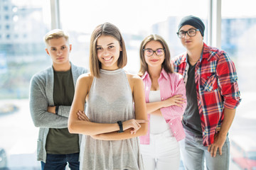 Successful team leader with a warm friendly smile standing with folded arms in front of the friends people