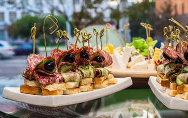 snacks assorted canapes with smoked sausage baked bread and olives with cucumber, close-up