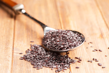 Black rice in a spoon, close-up, wooden background, horizontal, selective focus, high contrast