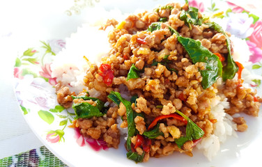 Spicy fried pork chops with basil on white plate with flower pattern