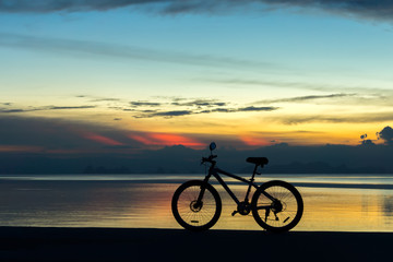 Obraz premium Silhouette of a bike on a lake at twilight.