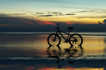 Fototapeta na wymiar Silhouette of a bike on a lake at twilight.