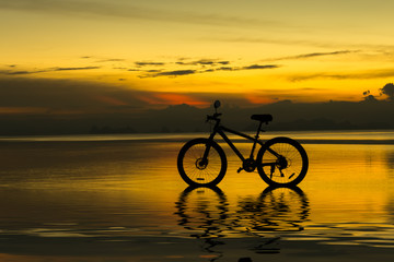 Fototapeta na wymiar Silhouette of a bike on a lake at twilight.