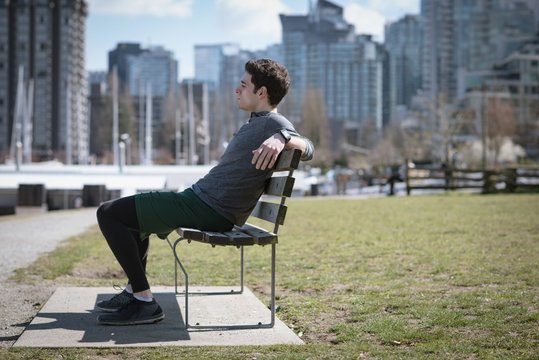 Side view of young man looking away while sitting on bench