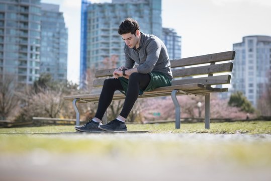 Surface level of young man checking time while sitting on bench