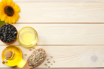 Sunflower oil, seeds and flower on white wooden background. top view with copy space