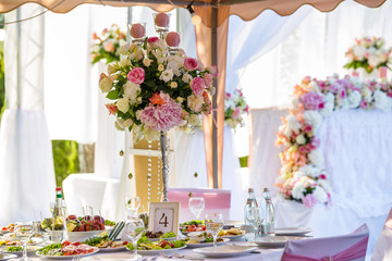 Served round banquet table outdoor in marquee decorated pink flowers and silk