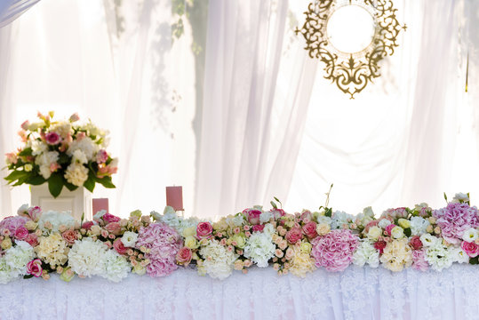 Served wedding banquet table in the garden decorated white lace, pink flowers and silk. newlyweds table