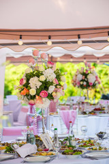 Served round banquet table outdoor in marquee decorated pink flowers and silk
