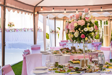 Served round banquet table outdoor in marquee decorated pink flowers and silk