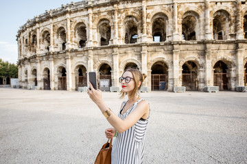 Lifestyle portrait of a young businesswoman walking near old roman amphitheatre in Nimes city, France