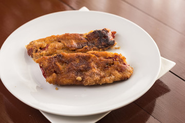 Fried grilled paprika in the eggs served on the white plate above brown table boards